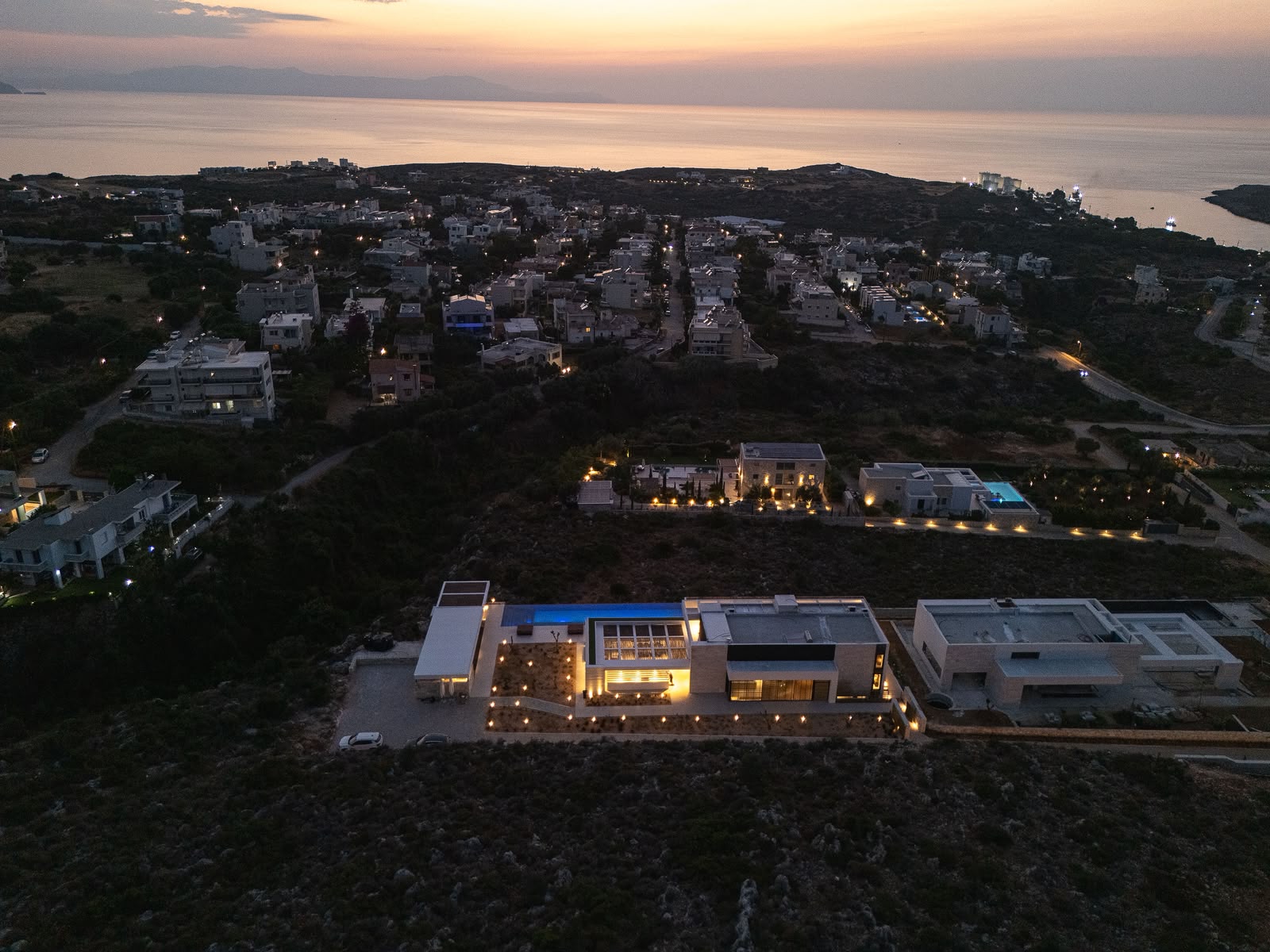 The estate lit at dusk above the coast